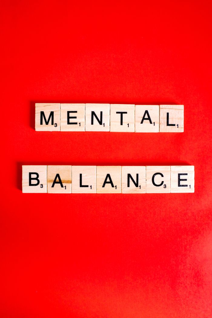 Wooden letter blocks spelling 'Mental Balance' on a bold red background, emphasizing mental health.