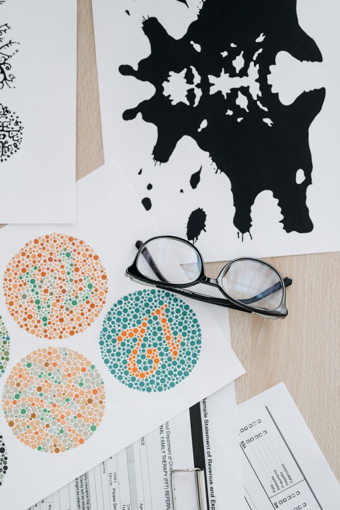 about-02 Flat lay of color blindness tests and inkblot cards with eyeglasses for vision assessment.
